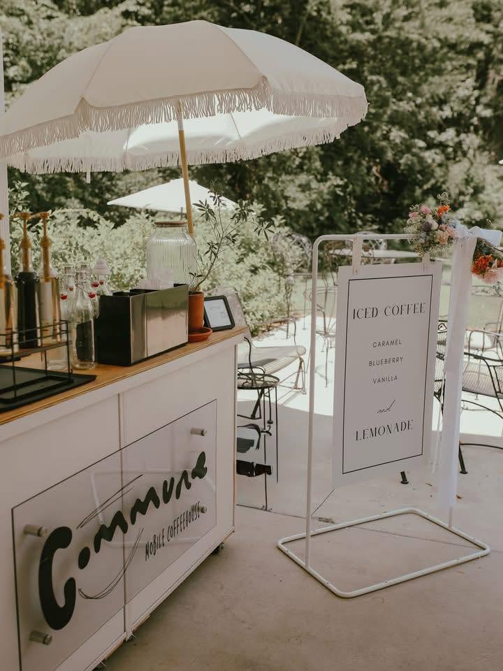 The Commune mobile coffee cart set up outdoors under a fringed umbrella